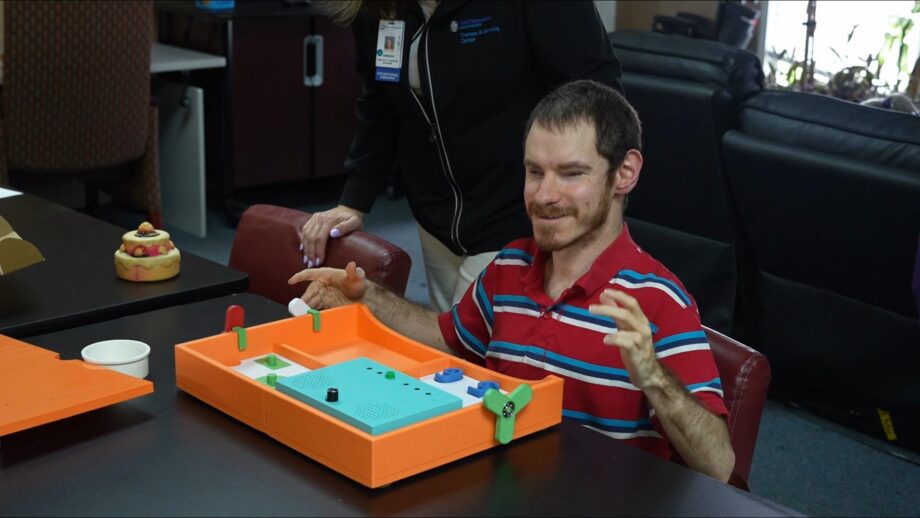 A person using a 3D printed tactile activity tray.