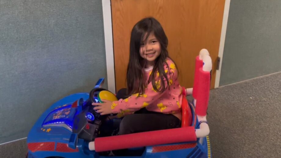A young student sat in an adaptive toy car with a switch activated accelerator.