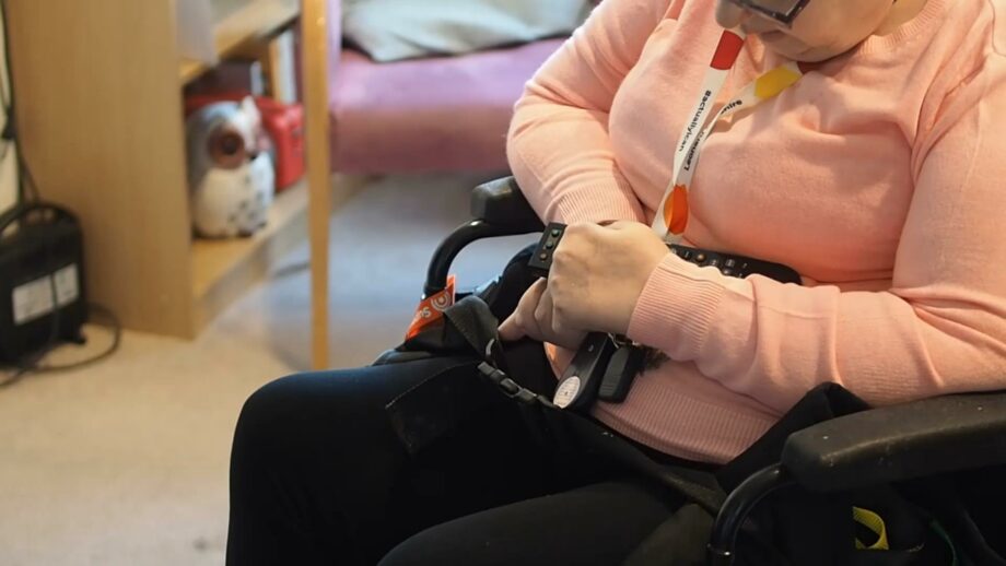 Make:able Champion, Bev, using her knuckles to press a button on her TV remote.