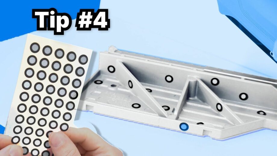 An engineering part with 3D scanner stickers spread across it.