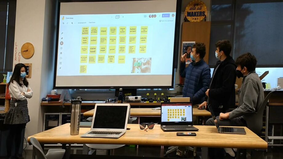 A team of students presenting a brainstorm on a projector screen.
