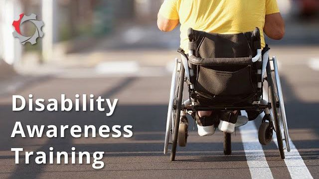 A person in a wheelchair on a road, with the title 'Disability Awareness Training' overlaid in white bold text.