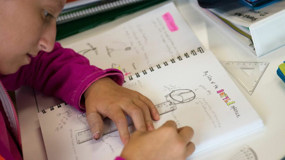 A student drawing assistive bottle opener ideas in her sketchbook.
