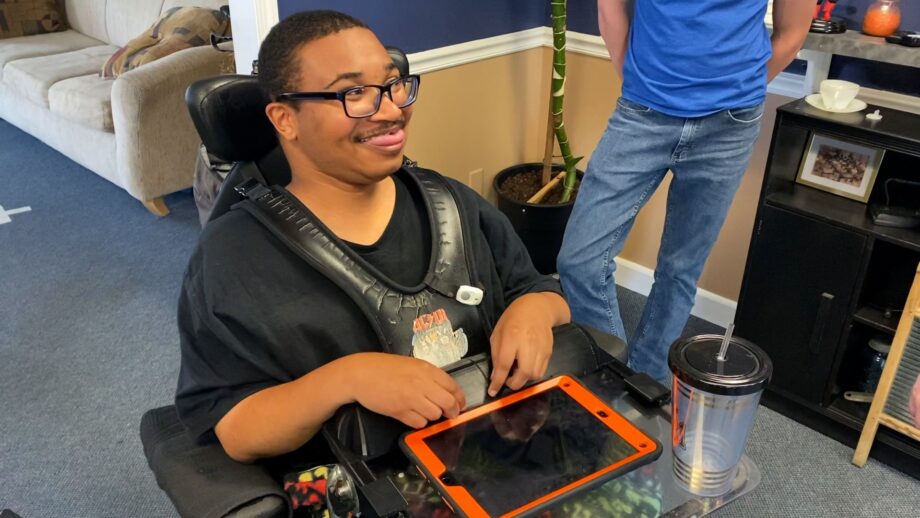 A person sat in a wheelchair with a 3d printed accessory tray.