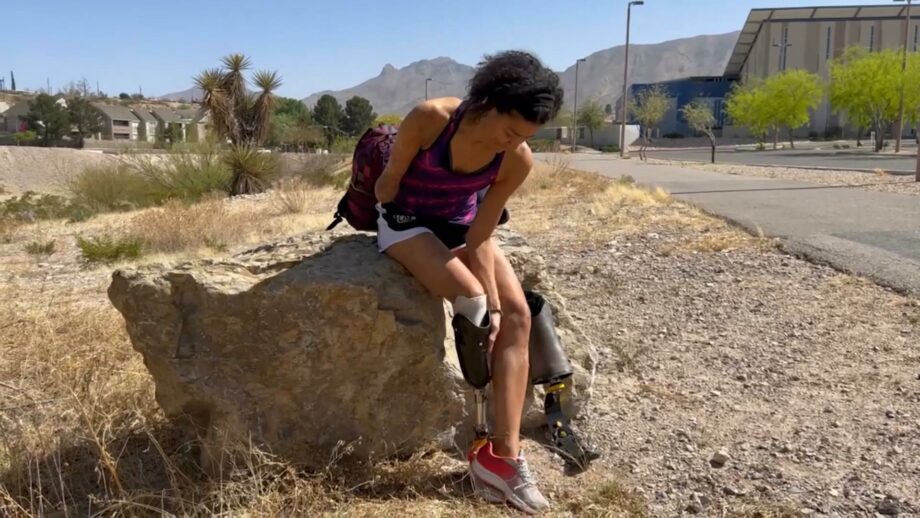 Make:able end user Juaisca sat on a rock adjusting her prosthetic leg.
