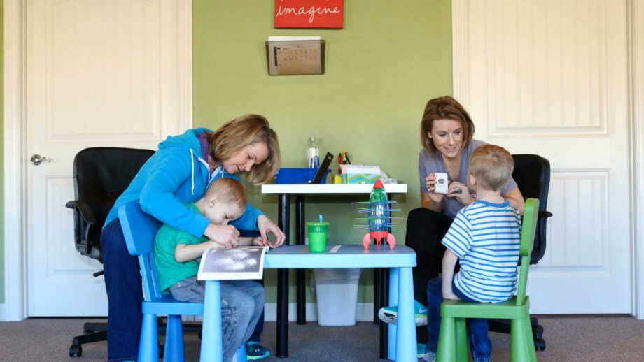 2 occupational therapists working with children at a table.