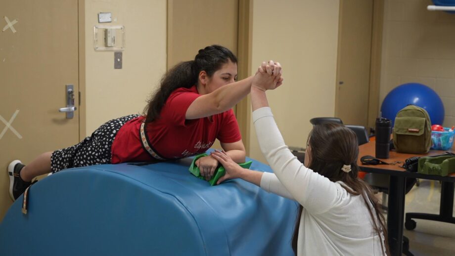 A student working with a therapist on hand and arm exercises, using a 3D printed support splint.