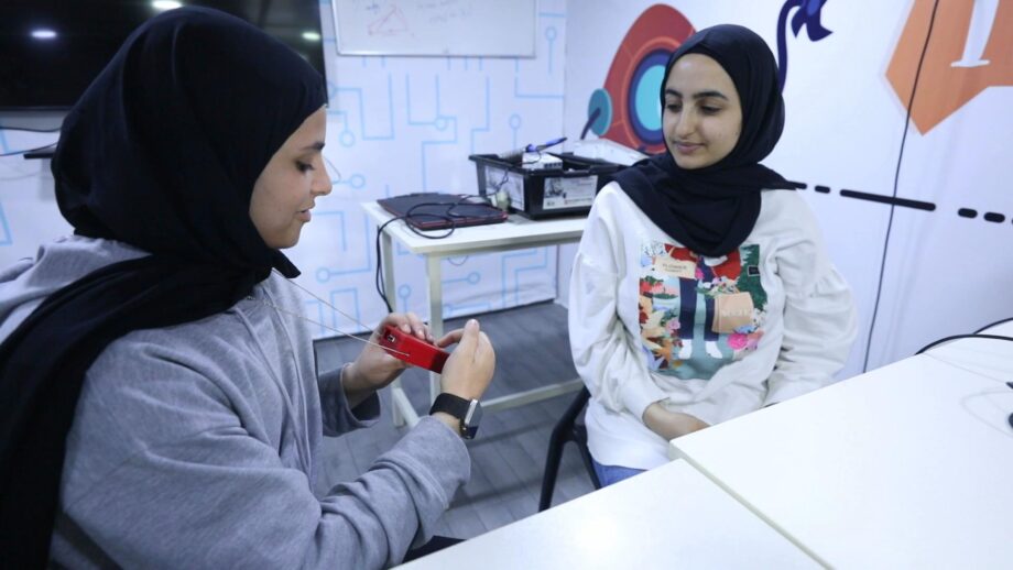 A student showing another student a 3D printed necklace device, which supports communication between deaf mothers and their children.