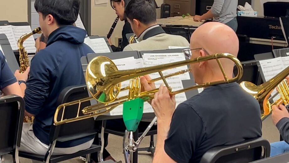 A teacher playing the trombone using a 3D printed support stand.