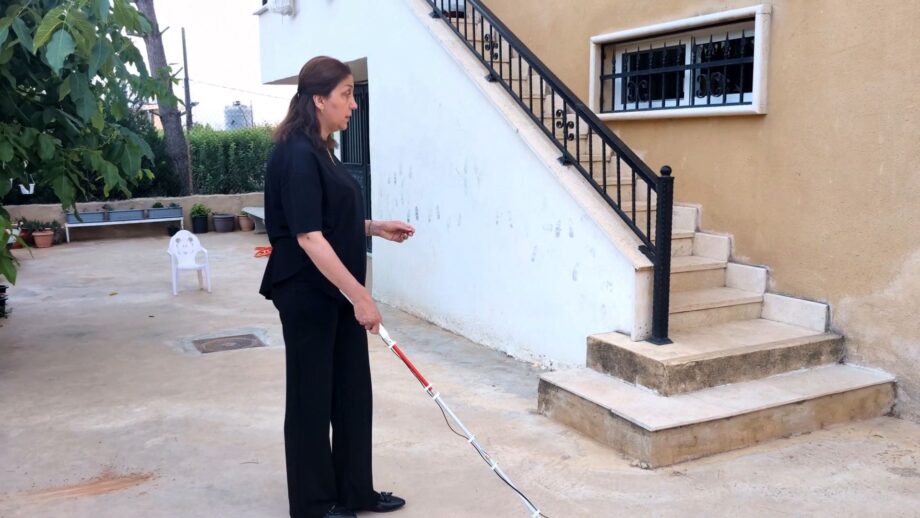 A person using a smart cane to navigate the outdoors.