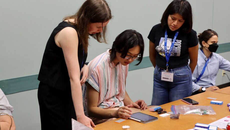 A student testing the Tap assistive switch during a workshop, using it to control an iPad through switch access while providing feedback to the designer.