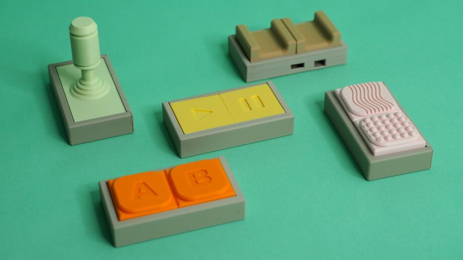A collection of Tap assistive switch modules arranged on a green background, showing different button styles and accessories.